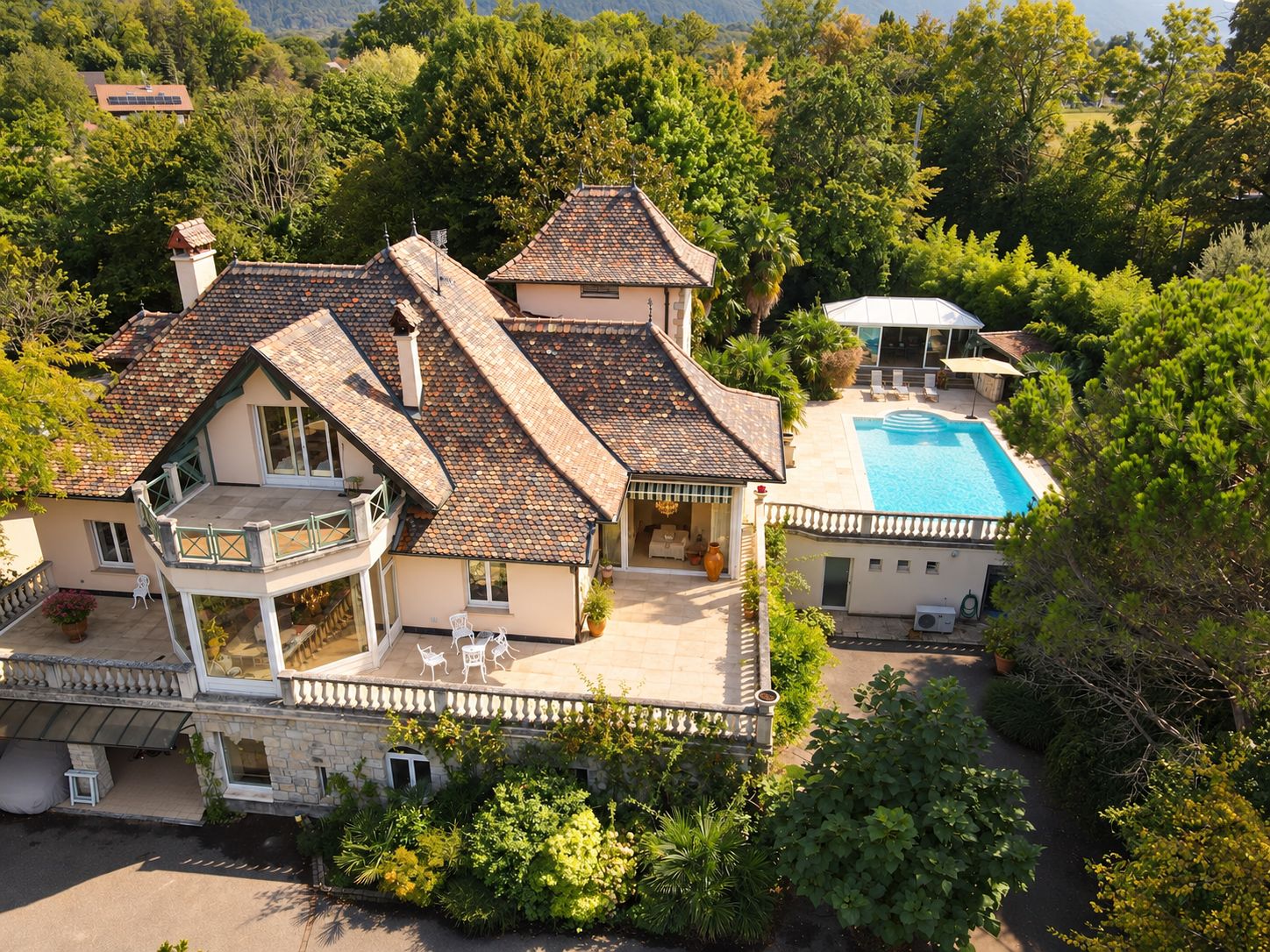 Clos des Savoyances from above: the tiled roofs, the tower, the terraces and the pool among mature trees. Enhanced photograph.